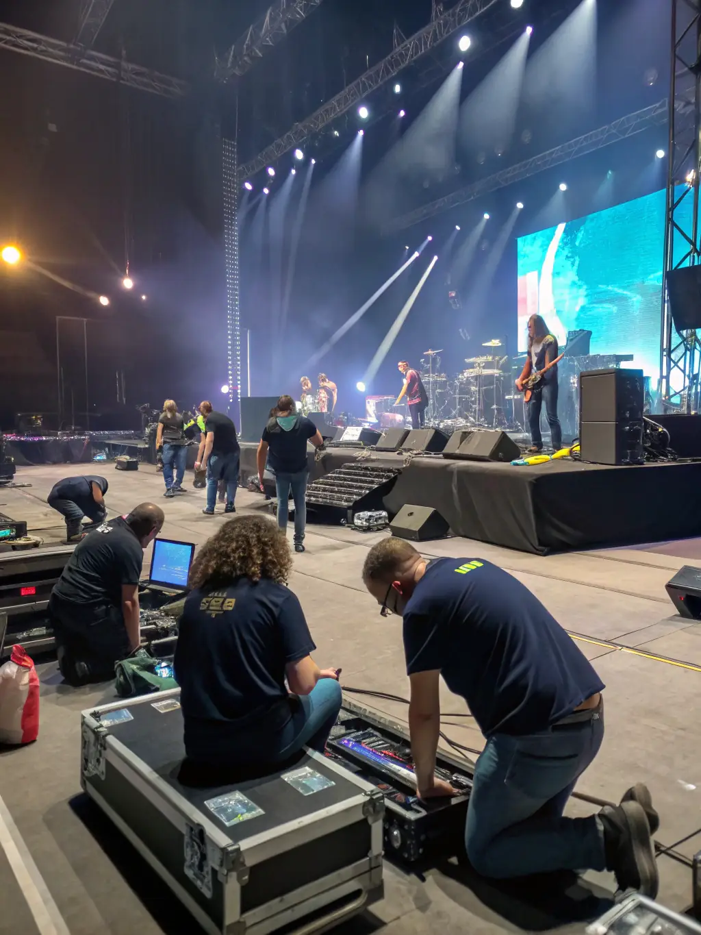 A photograph capturing a diverse group of volunteers actively setting up a stage for an outdoor concert, showcasing the collaborative spirit and dedication of PARFUMS DE SCENE.
